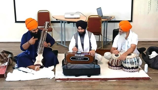 Three Sikh musicians with traditional instruments wearing turbens