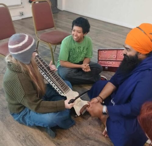Trying out a traditional instrument used in Sikh music