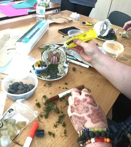 young person making a fairy garden using a teacup and saucer