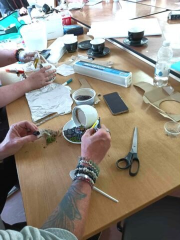 people making fairy gardens using teacups and saucers, only arms showing in the photograph