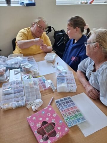 female crafter with two workshop attendees teaching them jewellery making